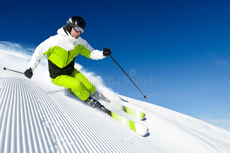 Esquiador en montañas, piste preparado y día asoleado