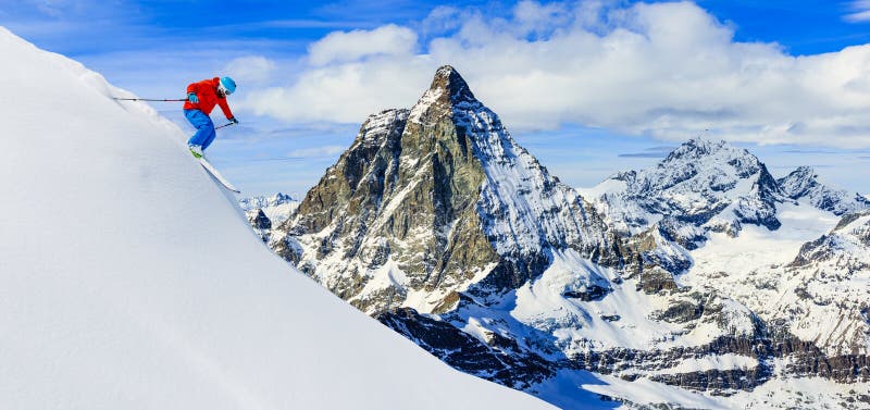 Esquiador que esquia para baixo nas montanhas altas na neve fresca do pó Sn