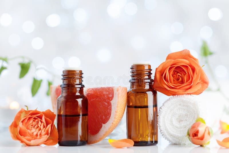 Essential oil bottles with towel, grapefruit and rose flowers on white table. Spa, aromatherapy, wellness, beauty background. stock image Essential oil bottles with towel, grapefruit and rose flowers on white table. Spa, aromatherapy, wellness, beauty background. stock image