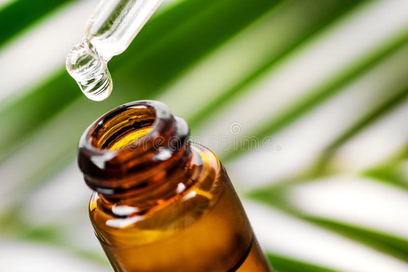 Essential oil dropping from pipette to the bottle