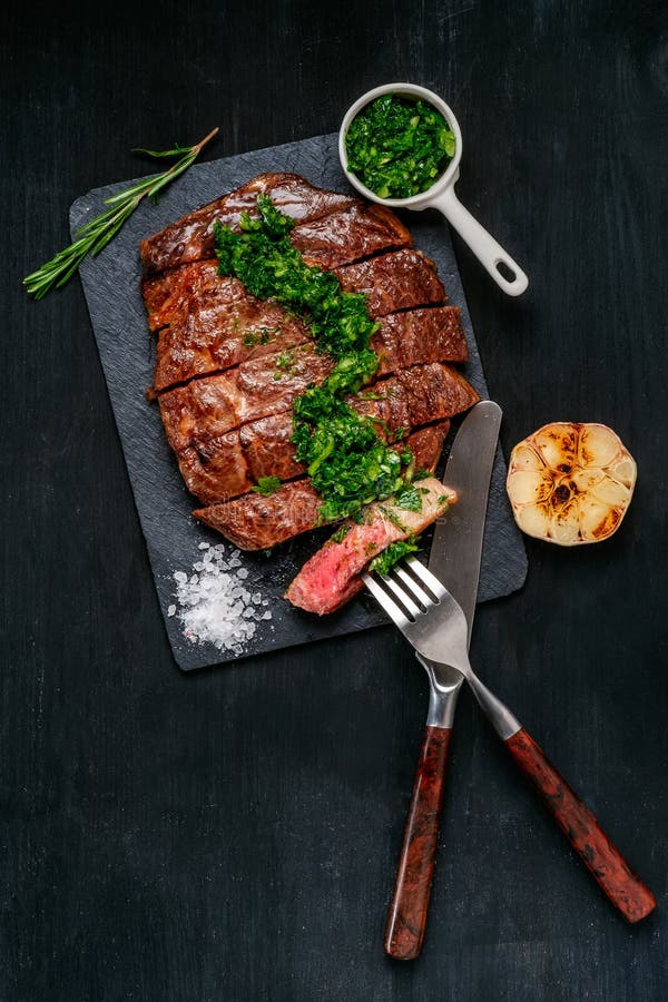 Essfertiges Schwarzes Angus-Rindfleischrippen-Augensteak Filets mit Kräutern Knoblauch und Soße auf Schieferbrett. Fertiggericht zum Abendessen auf dem Hintergrund des dunklen Schwarzen Holz. Draufsicht mit Kopienraum