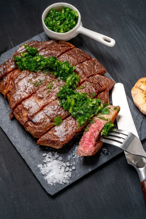 Essfertiges Schwarzes Angus-Rindfleischrippen-Augensteak Filets mit Kräutern Knoblauch und Soße auf Schieferbrett lizenzfreie stockfotos