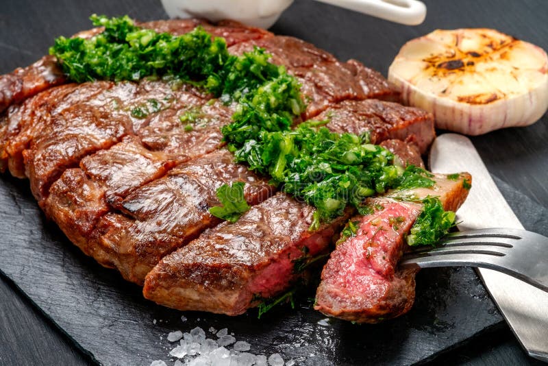 Essfertiges Schwarzes Angus-Rindfleischrippen-Augensteak Filets mit Kräutern Knoblauch und Soße auf Schieferbrett stockbilder
