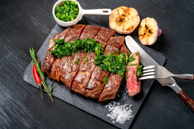Essfertiges Schwarzes Angus-Rindfleischrippen-Augensteak Filets mit Kräutern Knoblauch und Soße auf Schieferbrett lizenzfreie stockbilder