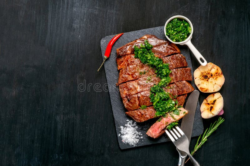Essfertiges Schwarzes Angus-Rindfleischrippen-Augensteak Filets mit Kräutern Knoblauch und Soße auf Schieferbrett lizenzfreie stockbilder