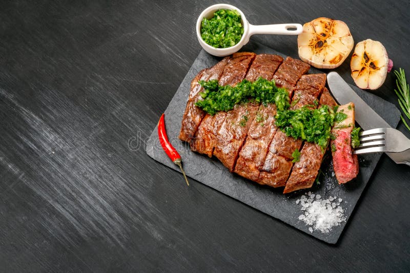 Essfertiges Schwarzes Angus-Rindfleischrippen-Augensteak Filets mit Kräutern Knoblauch und Soße auf Schieferbrett stockbild