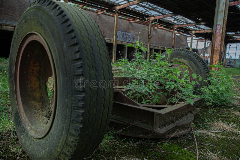 Essieu rouille renversé avec des plantes dans un entrepôt abandonné photographie stock