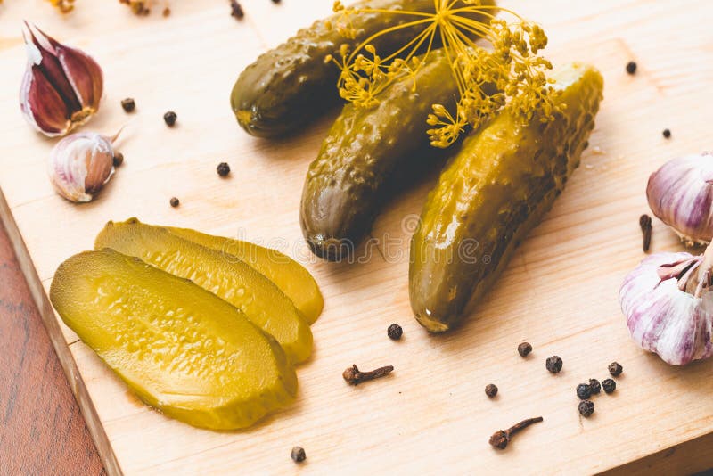 In Essig eingelegte grüne Gurken, frischer Knoblauch und Gewürze auf einem hölzernen Brett lizenzfreies stockfoto In Essig eingelegte grüne Gurken, frischer Knoblauch und Gewürze auf einem hölzernen Brett lizenzfreies stockfoto