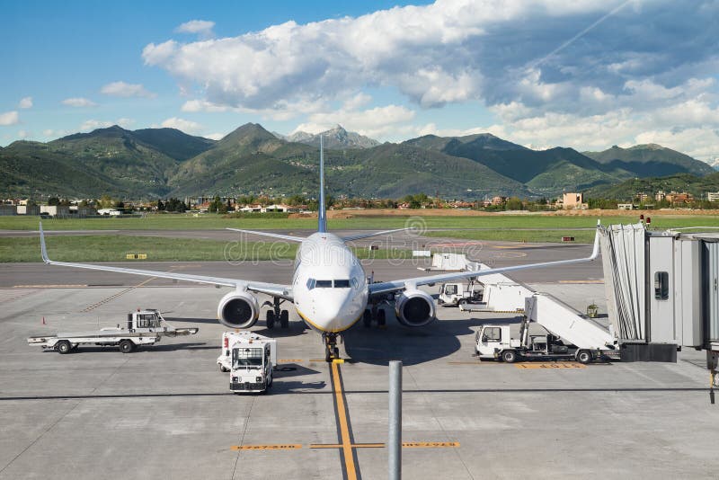 Estacionamiento del aeroplano de Airacraft en el aeropuerto cerca de las montañas verdes que son cargadas fotografía de archivo Estacionamiento del aeroplano de Airacraft en el aeropuerto cerca de las montañas verdes que son cargadas fotografía de archivo