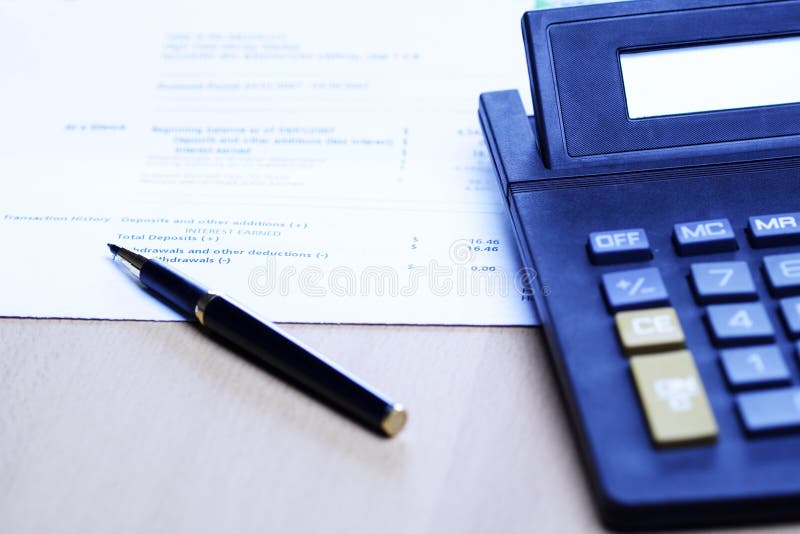 An image of a pen and a calculator on top of a financial statement, can be used for business finance and accounting concept ( shot in blue tone). An image of a pen and a calculator on top of a financial statement, can be used for business finance and accounting concept ( shot in blue tone)