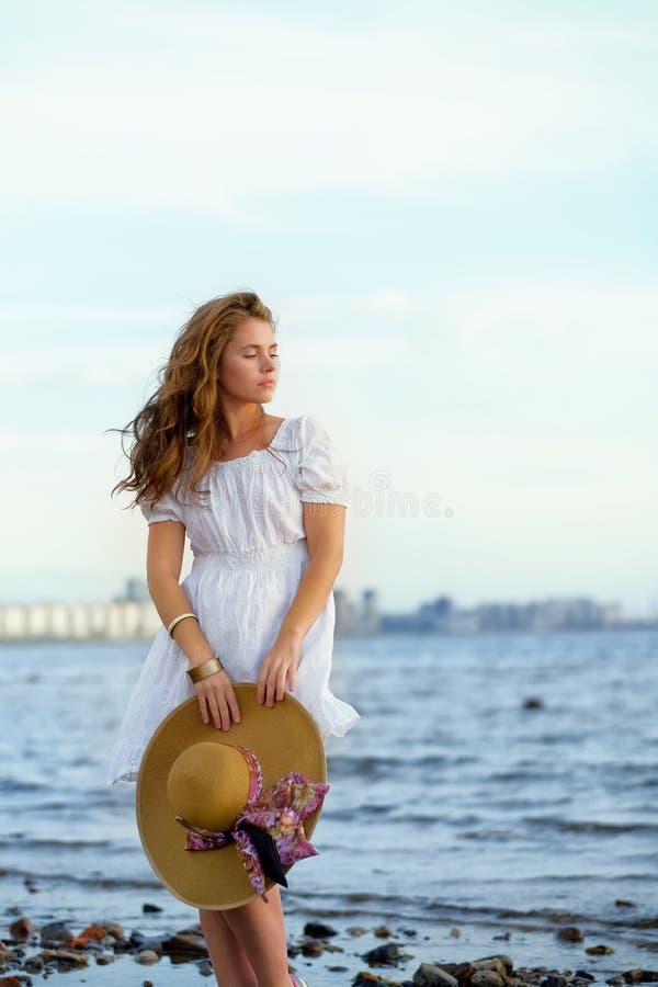 Estancia blanca del vestido de la chica joven que lleva en el coste del mar imagen de archivo libre de regalías Estancia blanca del vestido de la chica joven que lleva en el coste del mar imagen de archivo libre de regalías