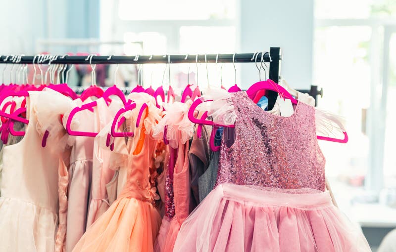 Estante con muchos vestidos hermosos del d?a de fiesta para las muchachas en suspensiones en la sala de exposici?n de la moda de imagen de archivo Estante con muchos vestidos hermosos del d?a de fiesta para las muchachas en suspensiones en la sala de exposici?n de la moda de imagen de archivo