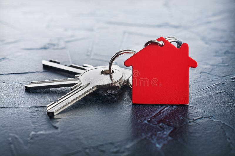 Estate concept with key, red keychain with house symbol, concrete