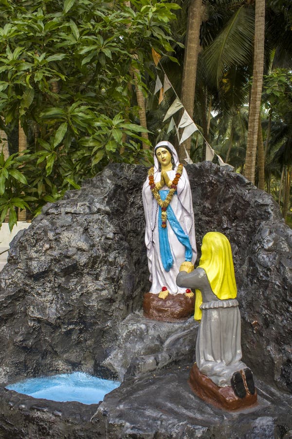 Estatua de la Virgen María en un primer de piedra en un fondo de palmeras verdes fotografía de archivo Estatua de la Virgen María en un primer de piedra en un fondo de palmeras verdes fotografía de archivo