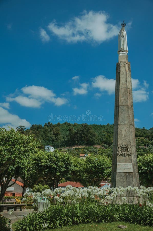 Estatua de nuestra señora sobre la picota en un jardín florecido imágenes de archivo libres de regalías Estatua de nuestra señora sobre la picota en un jardín florecido imágenes de archivo libres de regalías