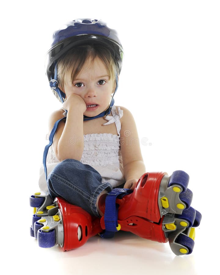 An adorable preschooler weepy because her plastic roller blades made her fall. On a white background. An adorable preschooler weepy because her plastic roller blades made her fall. On a white background.