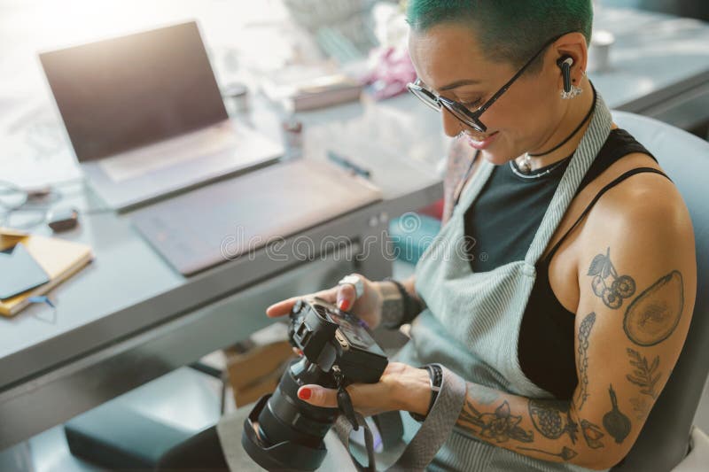 Designer in eyeglasses looks on shoot in camera screen during working in own design studio. Designer in eyeglasses looks on shoot in camera screen during working in own design studio