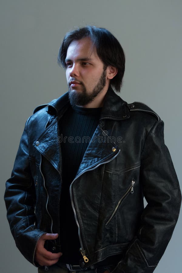 Estilo da rocha ou do motociclista Retrato de um indivíduo brutal com uma barba em um casaco de cabedal preto imagem de stock Estilo da rocha ou do motociclista Retrato de um indivíduo brutal com uma barba em um casaco de cabedal preto imagem de stock