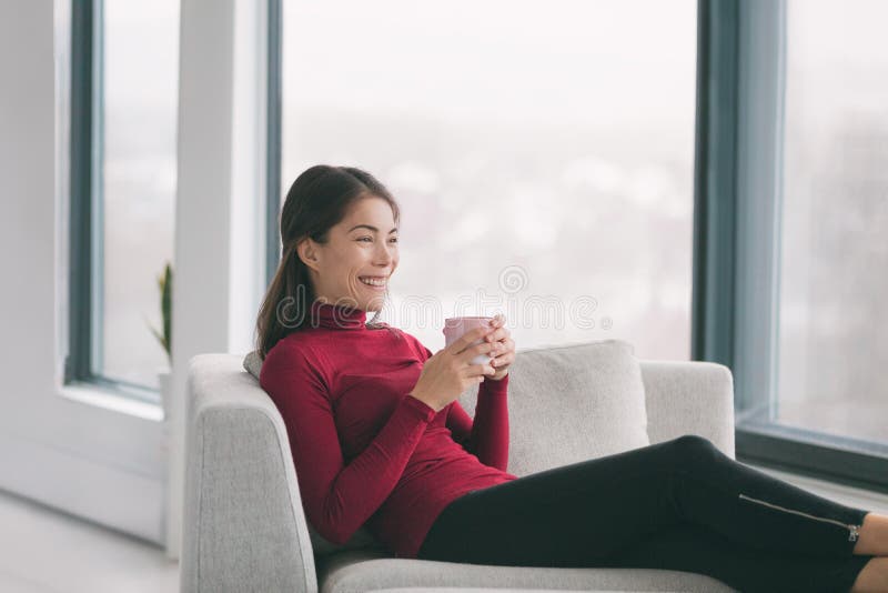 Garota feliz com telefone relaxa no sofá ou no sofá da sala