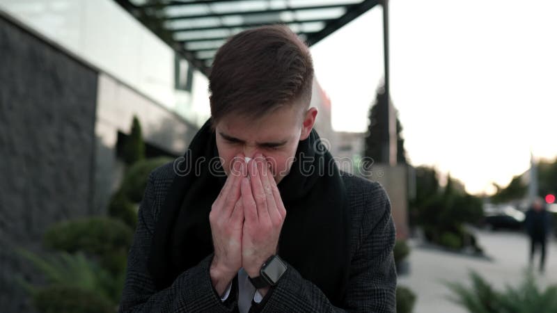 Estornudar y toser en forma jóven lucha con síntomas de gripe al aire libre almacen de metraje de vídeo
