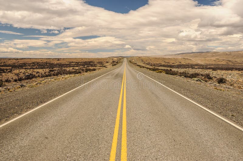 Estrada asfaltada vazia americana do deserto do baixo ângulo com montanhas e nuvens no fundo EL Calafate a Puerto Natales fotografia de stock Estrada asfaltada vazia americana do deserto do baixo ângulo com montanhas e nuvens no fundo EL Calafate a Puerto Natales fotografia de stock