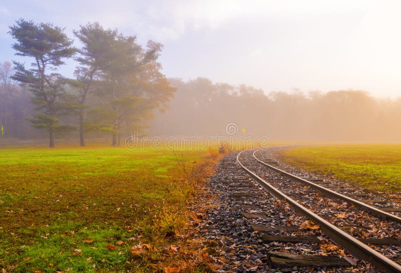 Railroad tracks going into the foggy forest on the beautiful autumn morning. Railroad tracks going into the foggy forest on the beautiful autumn morning