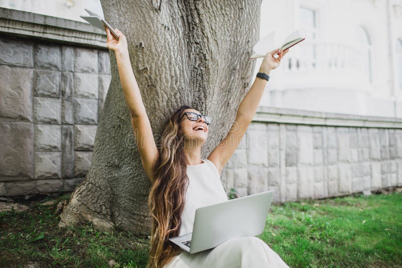Estudante bonita que aprende suas lições que sentam-se na grama fotografia de stock Estudante bonita que aprende suas lições que sentam-se na grama fotografia de stock