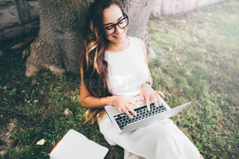 Estudante bonita que aprende suas lições que sentam-se na grama foto de stock royalty free Estudante bonita que aprende suas lições que sentam-se na grama foto de stock royalty free