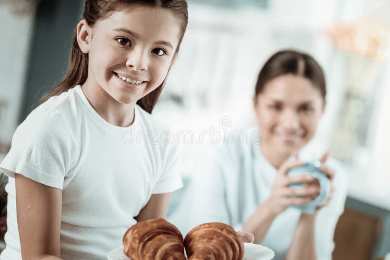 Estudante bonito que come croissant saborosos na cozinha imagens de stock Estudante bonito que come croissant saborosos na cozinha imagens de stock