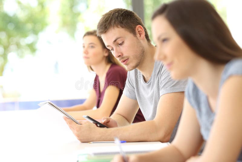 Estudante confundido com um telefone durante uma classe fotografia de stock royalty free Estudante confundido com um telefone durante uma classe fotografia de stock royalty free