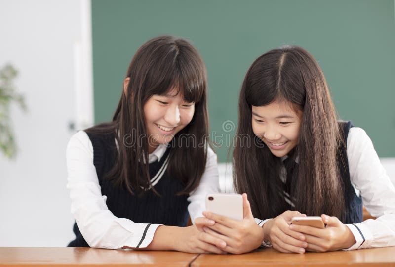 Estudante do adolescente que olha o telefone esperto na sala de aula fotografia de stock Estudante do adolescente que olha o telefone esperto na sala de aula fotografia de stock