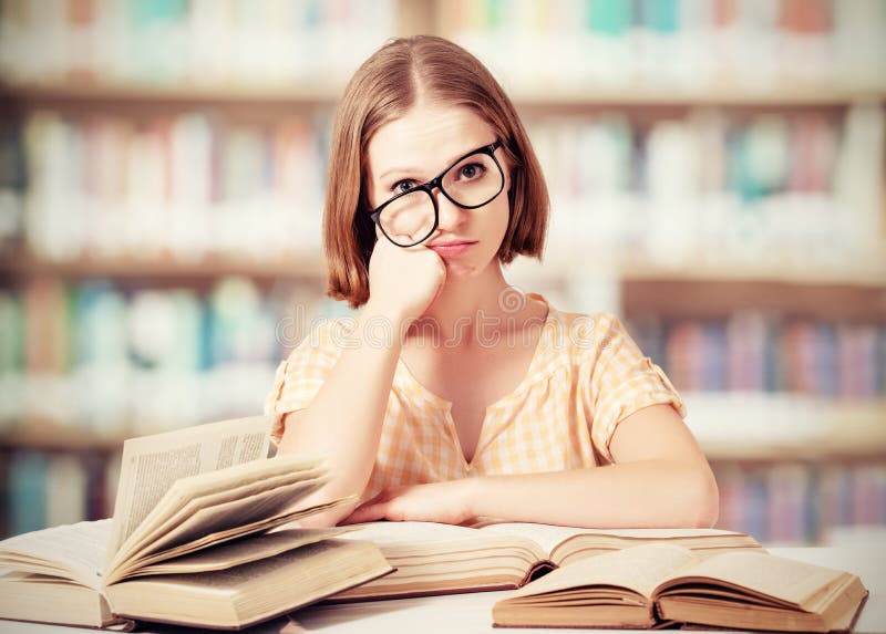 Estudante engraçada cansado com os livros de leitura dos vidros foto de stock Estudante engraçada cansado com os livros de leitura dos vidros foto de stock