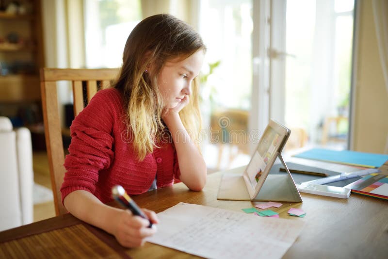 Estudante esperta que faz seus trabalhos de casa com tabuleta digital em casa Criança que usa dispositivos para estudar Educação fotografia de stock Estudante esperta que faz seus trabalhos de casa com tabuleta digital em casa Criança que usa dispositivos para estudar Educação fotografia de stock