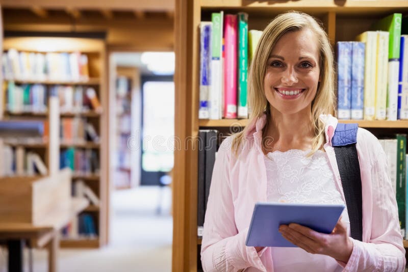 Estudante fêmea que usa a tabuleta na biblioteca foto de stock Estudante fêmea que usa a tabuleta na biblioteca foto de stock