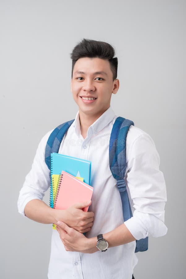 Estudante masculino asiático ocasional feliz que mantém livros isolados em um cinza imagens de stock Estudante masculino asiático ocasional feliz que mantém livros isolados em um cinza imagens de stock