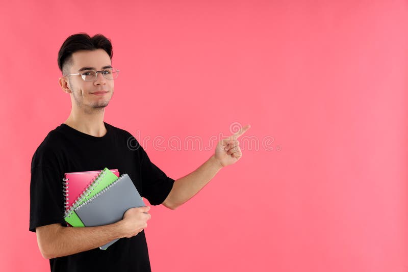 Estudante masculino com cadernos em fundo cor-de-rosa imagens de stock