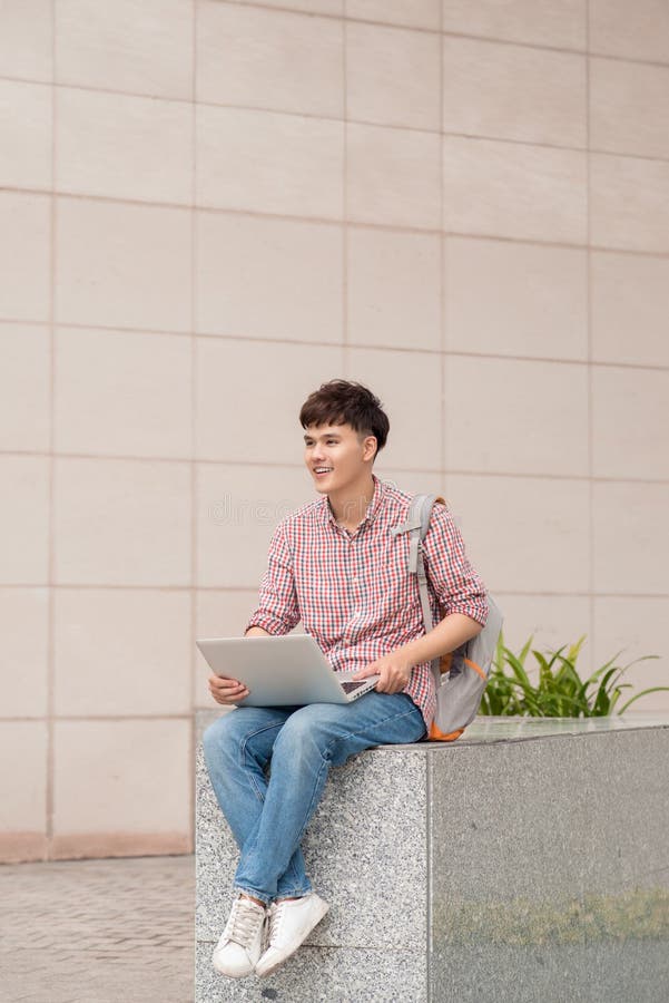 Estudante masculino que usa o portátil no terreno da faculdade imagens de stock Estudante masculino que usa o portátil no terreno da faculdade imagens de stock
