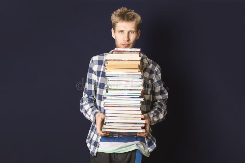 Estudante ocasional para levar a pilha enorme de livros no fundo escuro f fotografia de stock royalty free Estudante ocasional para levar a pilha enorme de livros no fundo escuro f fotografia de stock royalty free