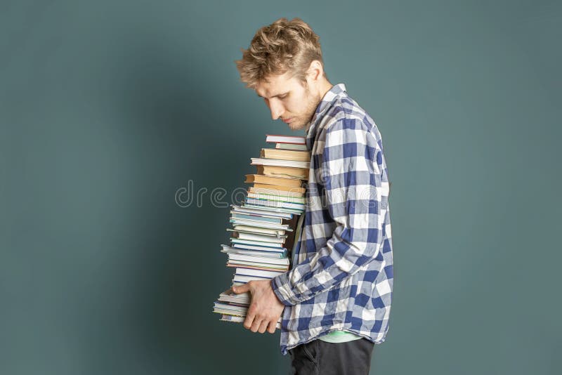 Estudante ocasional para levar a pilha enorme de livros no fundo escuro f fotos de stock Estudante ocasional para levar a pilha enorme de livros no fundo escuro f fotos de stock