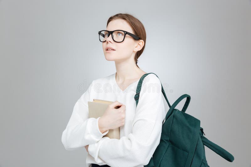Estudante pensativa com a trouxa que guarda o livro e o pensamento foto de stock Estudante pensativa com a trouxa que guarda o livro e o pensamento foto de stock