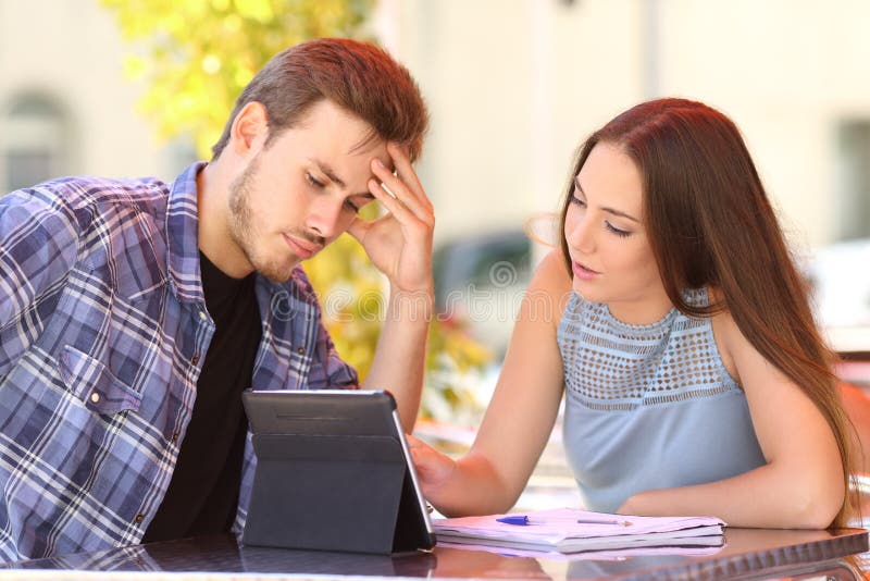 Estudante preocupado que aprende com um ensino do amigo imagem de stock Estudante preocupado que aprende com um ensino do amigo imagem de stock