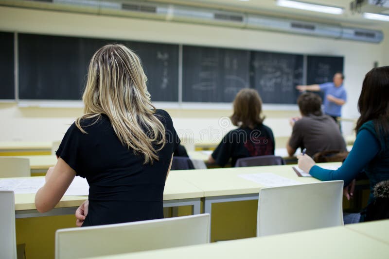 Estudante universitário fêmea que senta-se em uma sala de aula