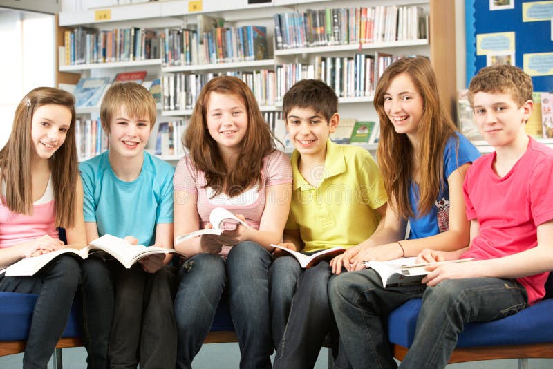 Estudantes adolescentes em livros de leitura da biblioteca foto de stock Estudantes adolescentes em livros de leitura da biblioteca foto de stock