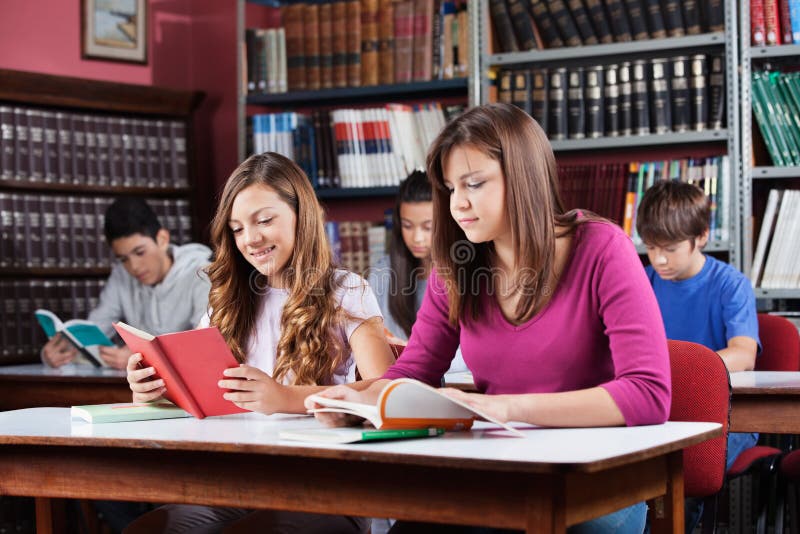 Estudantes adolescentes que estudam na biblioteca fotos de stock Estudantes adolescentes que estudam na biblioteca fotos de stock