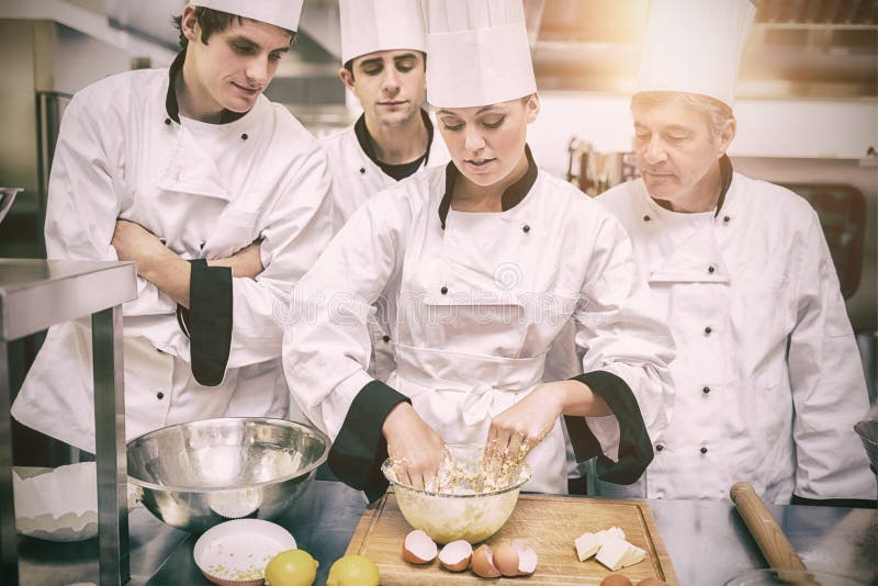 Estudantes culinários que aprendem como misturar a massa foto de stock royalty free Estudantes culinários que aprendem como misturar a massa foto de stock royalty free