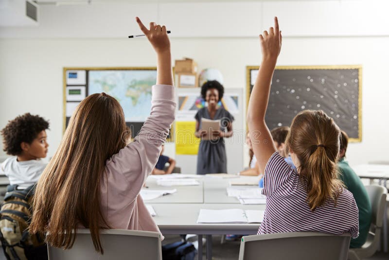 Estudantes da High School que levantam as mãos para responder à pergunta ajustada pelo professor In Classroom