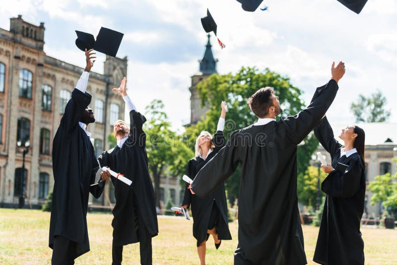 estudantes graduados novos que jogam acima tampões da graduação fotos de stock estudantes graduados novos que jogam acima tampões da graduação fotos de stock
