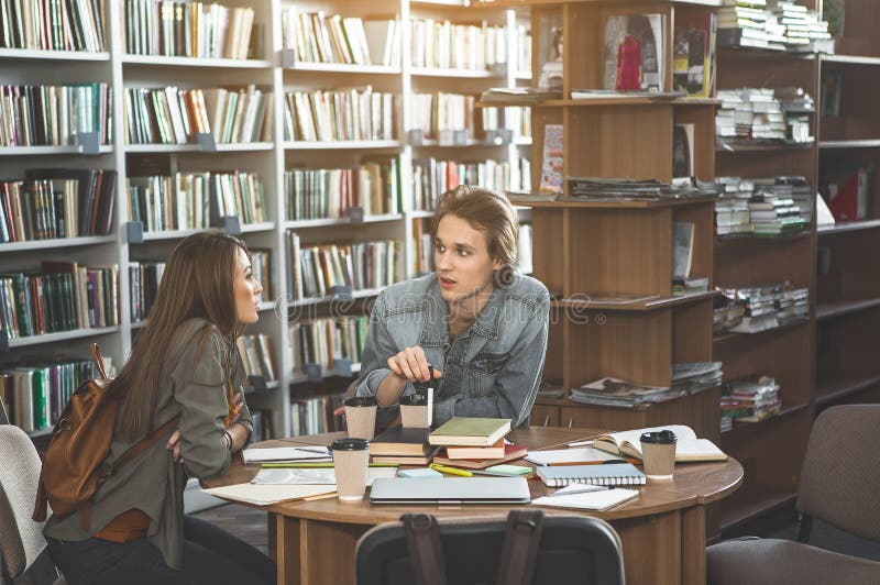 Estudantes serenos que aprendem na biblioteca imagem de stock Estudantes serenos que aprendem na biblioteca imagem de stock
