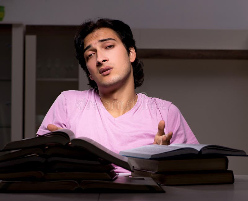 Estudiante apuesto de sexo masculino que se prepara para los exámenes tarde en casa fotografía de archivo