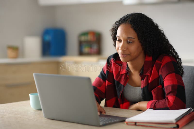 Estudiante de seriedad negra estudiando usando una laptop en la cocina fotos de archivo libres de regalías